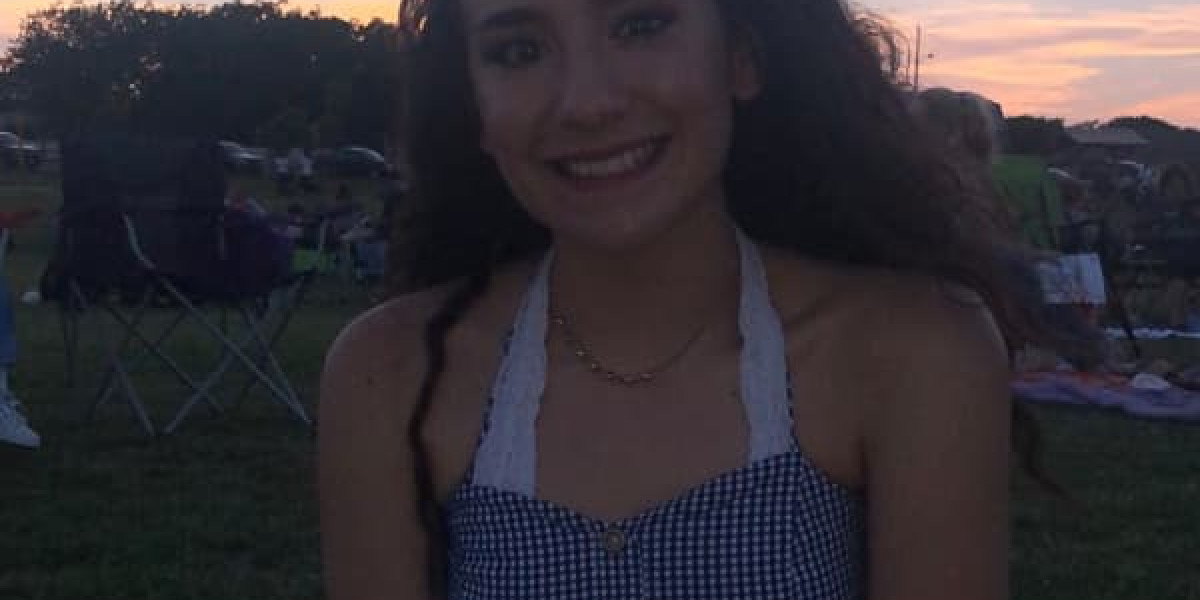 A person with long dark hair smiles while sitting outdoors, enjoying their spare time. They wear a checkered top and a necklace, surrounded by camping chairs and people in the background as the Texas sunset paints the park beautifully.