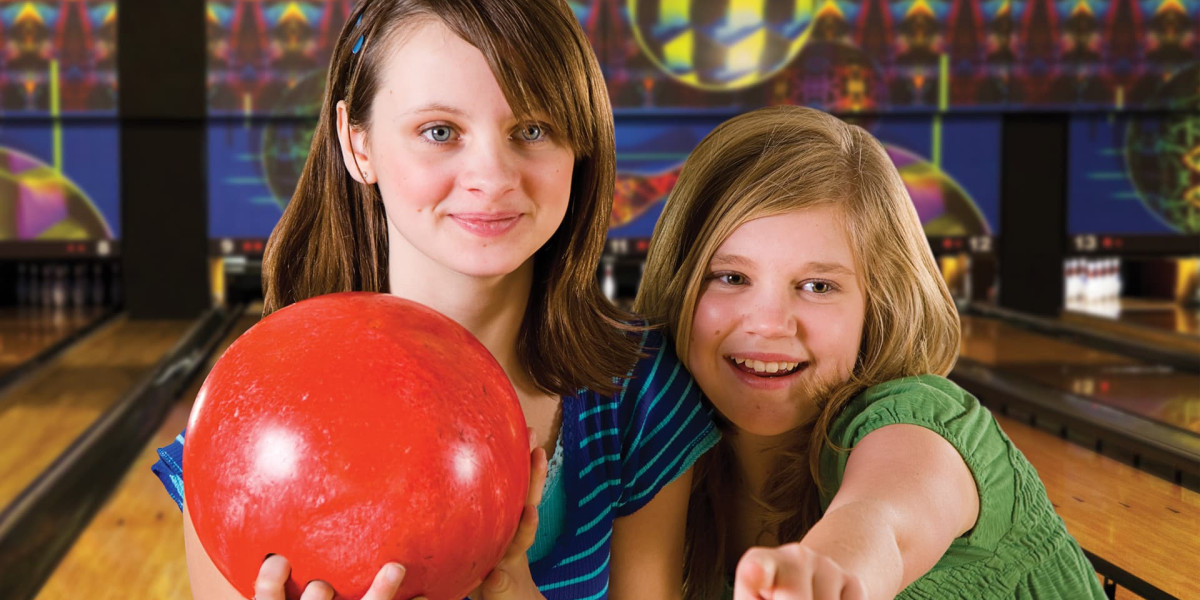 At Spare Time Texas, two children at the family fun center share smiles. One holds a red bowling ball, ready to play, while the other excitedly points forward. The vibrant lanes and colorful pins in the background promise a memorable bowling adventure.
