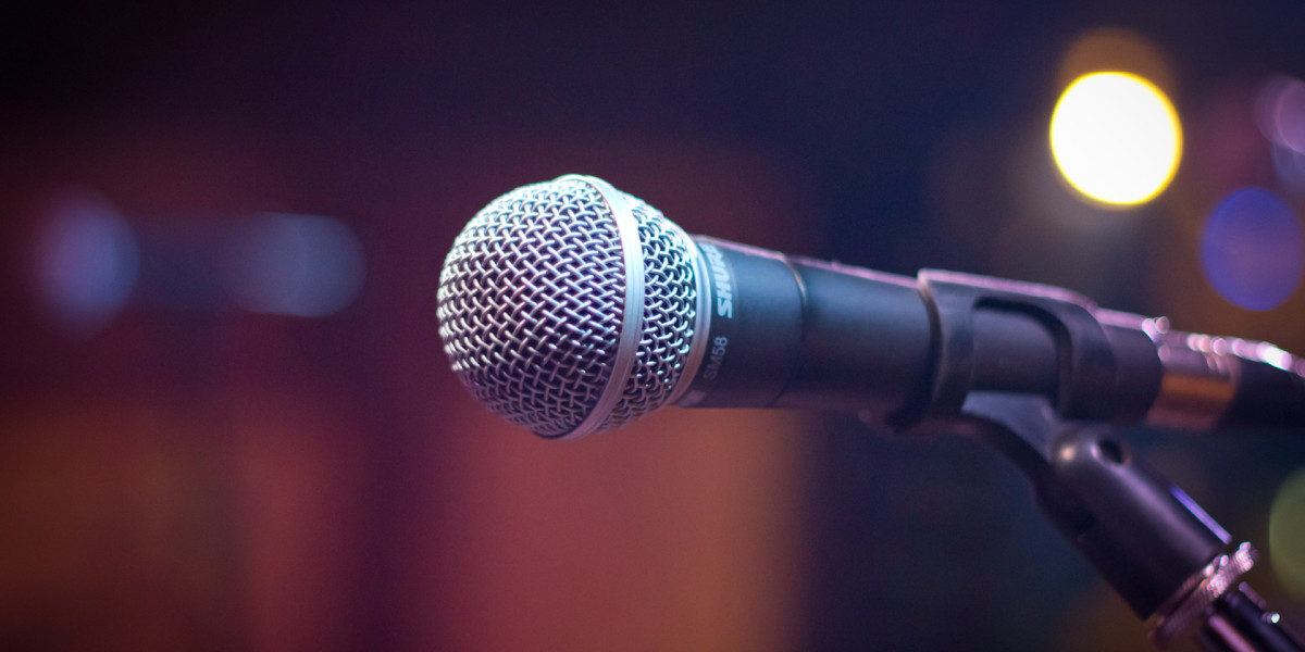 Close-up of a microphone on a stand against a blurred, colorful background with bokeh lights, reminiscent of the vibrant energy at Spare Time Texas. The image captures the performance or presentation atmosphere that mirrors the lively spirit found at this family fun center.