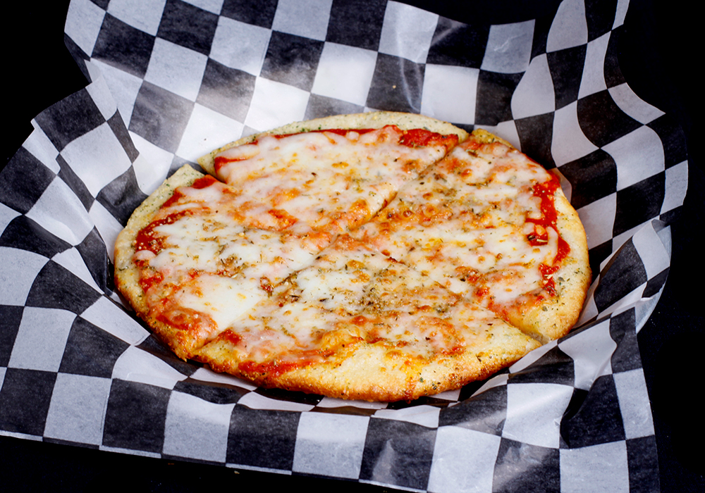 A freshly baked cheese pizza with a golden crust, topped with melted cheese and herbs, hails from the Spare Time Texas family fun center, where you can enjoy delicious bites between thrilling bowling matches. Placed on black and white checkered paper, it’s a perfect slice of joy.
