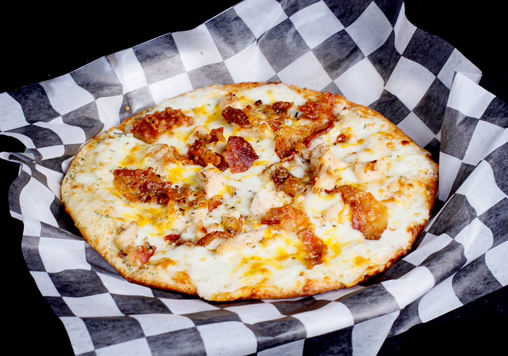 A delicious pizza with crispy bacon, juicy pieces of chicken, and melted cheese on a thin crust, perfect for sharing at Spare Time Texas. Enjoy this delightful treat while taking a break from the lanes at your favorite bowling spot.