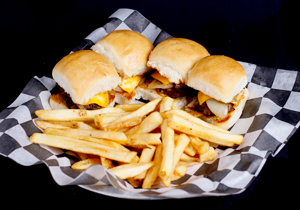 At Spare Time Texas, enjoy a plate of three cheeseburger sliders with melted cheese and grilled onions on soft buns. They're served alongside golden crispy French fries on black and white checkered paper—perfect for refueling after a round of bowling or other family fun center activities.