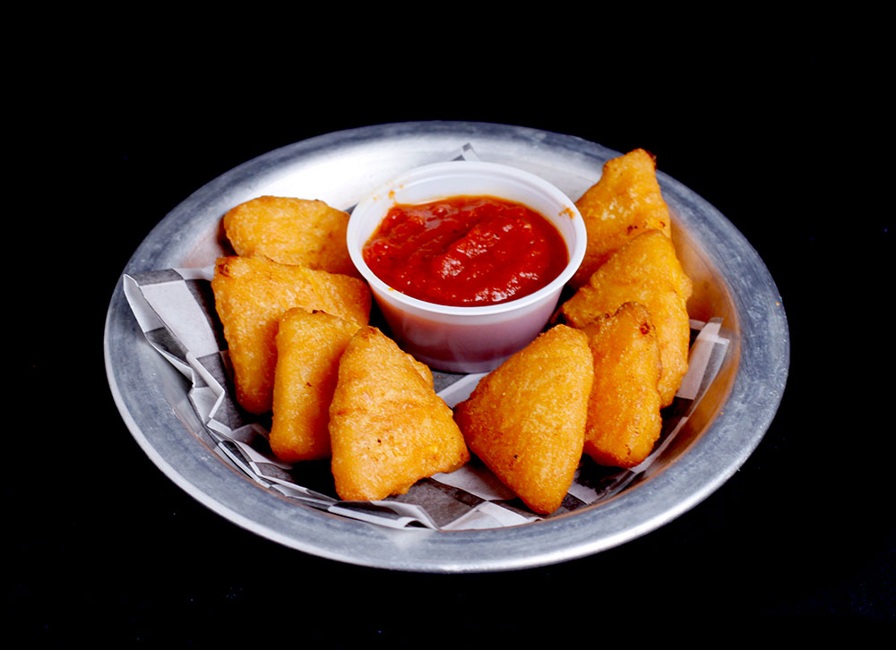 A plate of golden triangular fritters arranged neatly around a small cup of tomato-based red sauce, set against a dark background at Spare Time Texas. Perfect for a snack during bowling, these fritters rest invitingly on a bed of parchment paper, adding to the family fun center vibe.