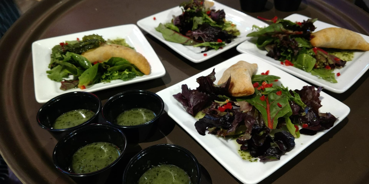 Plates of fresh salad with mixed greens and red peppers, each served with a flaky pastry, are perfect after a game at Spare Time Texas. Three small cups of green dressing accompany the dishes on a round tray, adding to the family fun center experience.