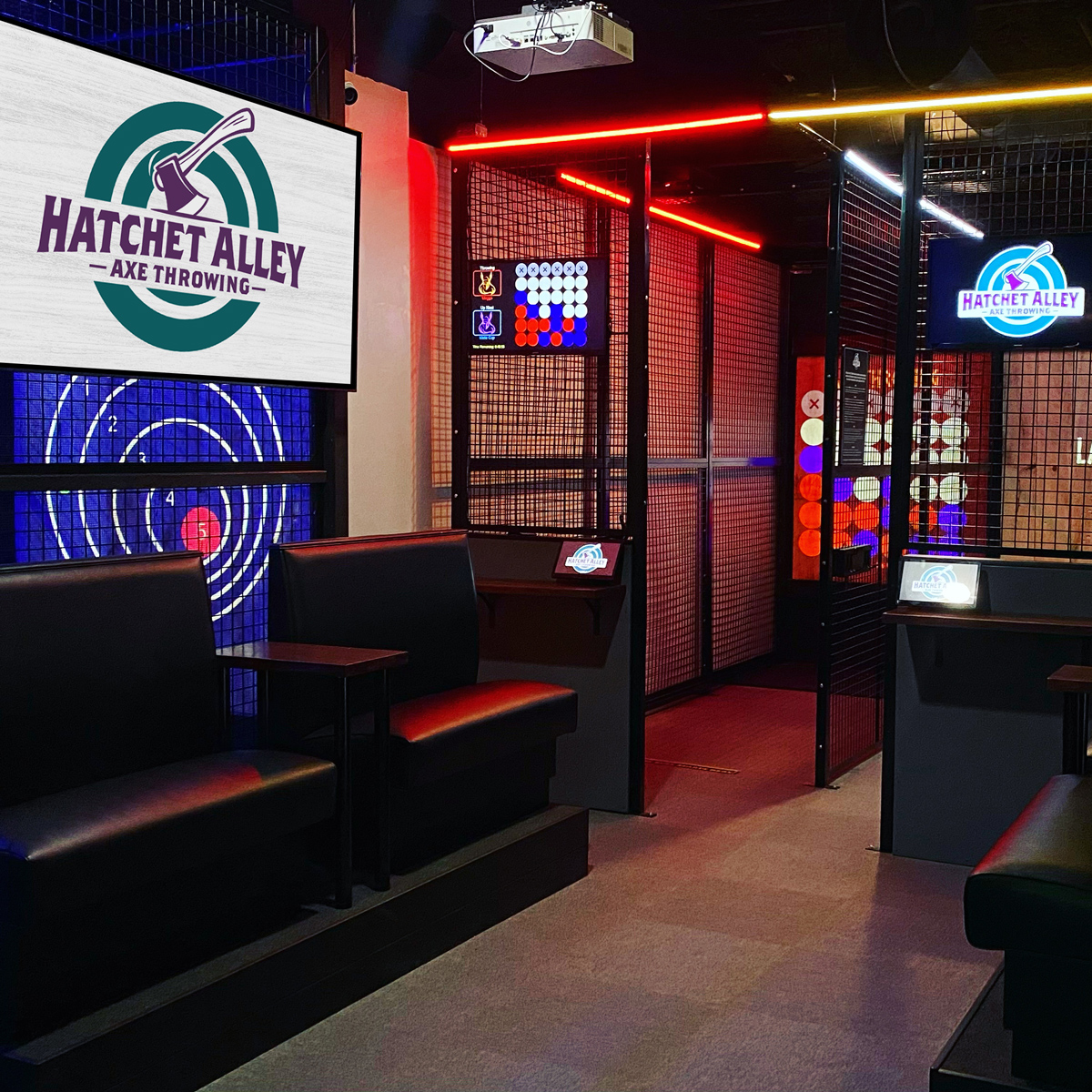A cozy axe throwing venue, part of the Spare Time Texas family fun center, features a sign that reads "Hatchet Alley Axe Throwing." Targets are set in lanes with black couches for seating. The atmosphere is warmly lit with neon lights, making it perfect for a thrilling family outing.