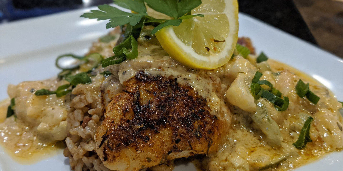 A plate of blackened fish topped with creamy sauce, garnished with chopped green onions and a lemon slice, served on rice, makes the perfect meal after a day of bowling at Spare Time Texas. A sprig of fresh parsley sits on top, adding a touch of green to the dish.