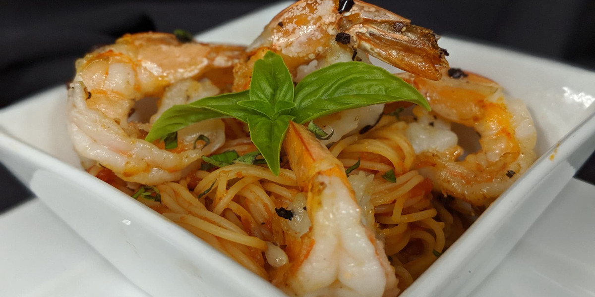 A white square dish filled with spaghetti, topped with cooked shrimp and garnished with a fresh basil leaf, makes for a delightful bite. Perfect for sharing at Spare Time Texas after a game of bowling at the family fun center, where meals are as exciting as the strikes you score.